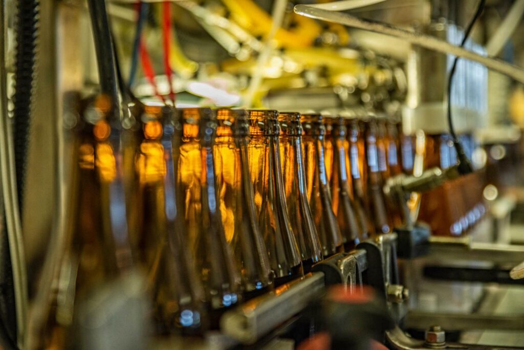 Tyhjät, ruskeat olut pullot kulkevat linjastolla täytettäväksi